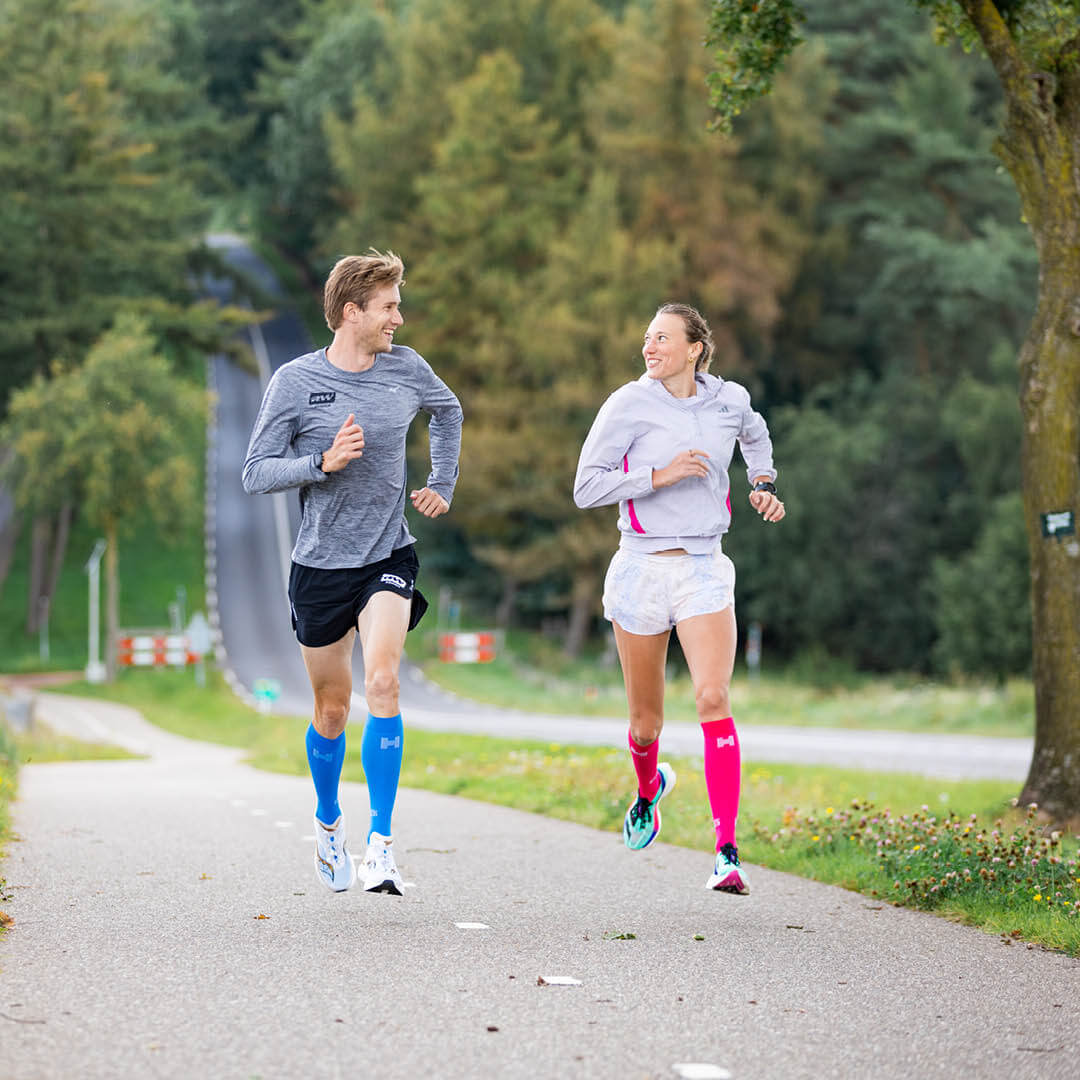 Man en vrouw hardlopen over straat en dragen de Pro Compressiekousen.