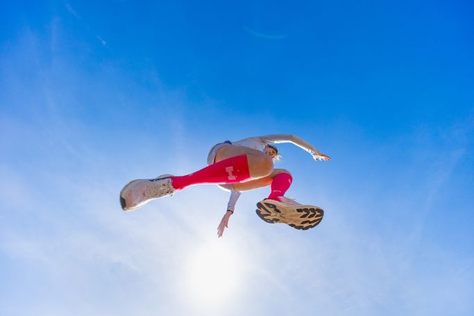 Blauwe lucht met springende vrouw in roze kousen
