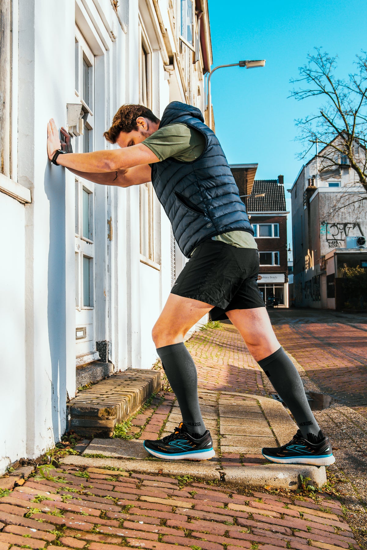 Hardloper stretcht bij een muur als warming-up. 